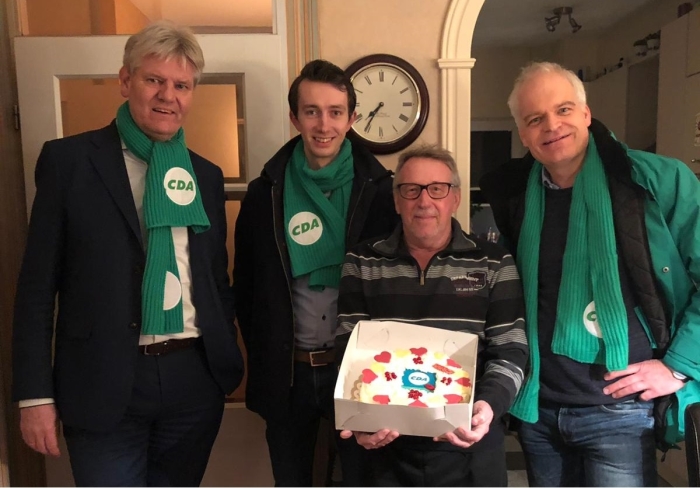Jan Wagenaar neemt een taart in ontvangst van Bert Komdeur