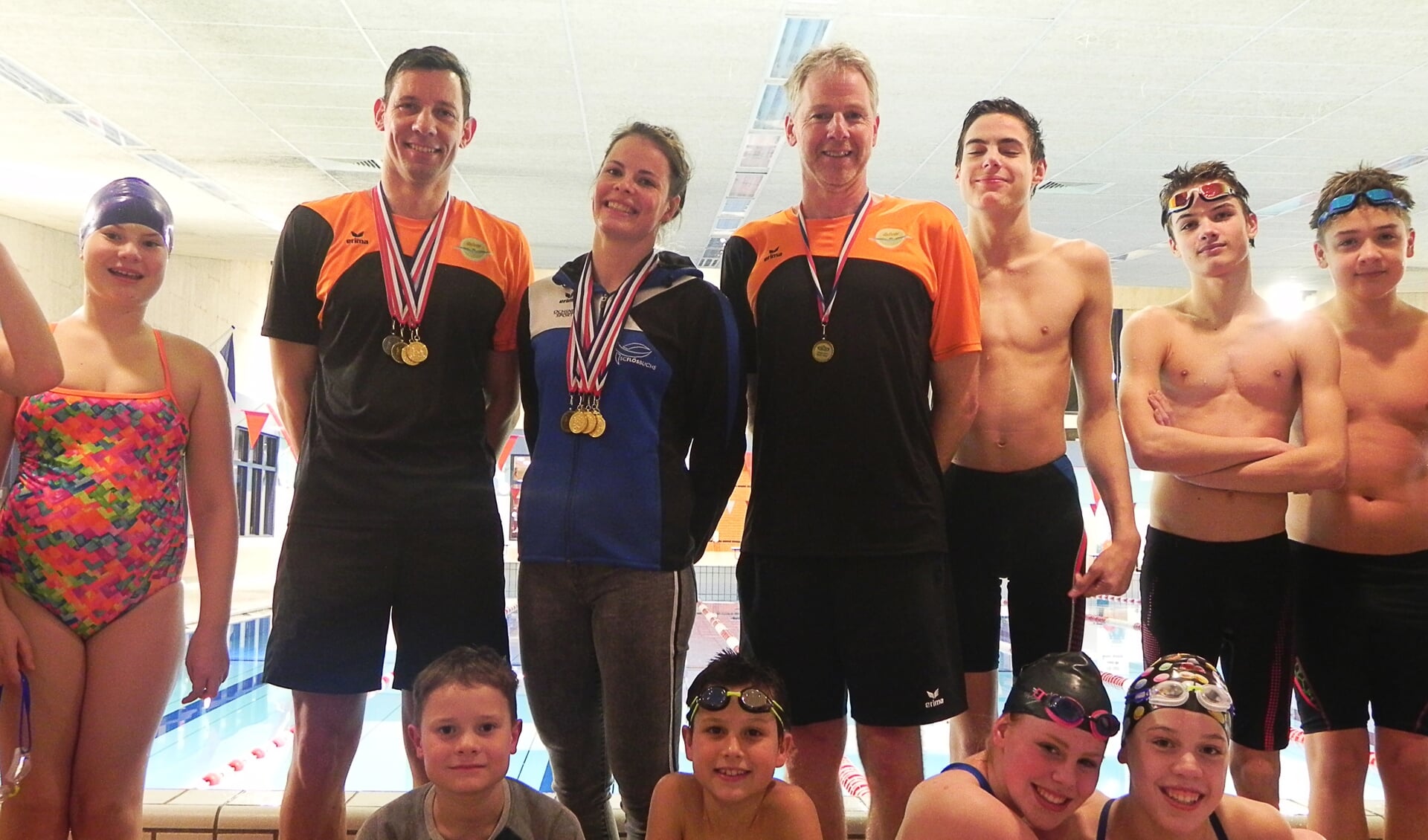 De medaillewinnaars van het ONMK, geflankeerd door jeugdige zwemtalenten.