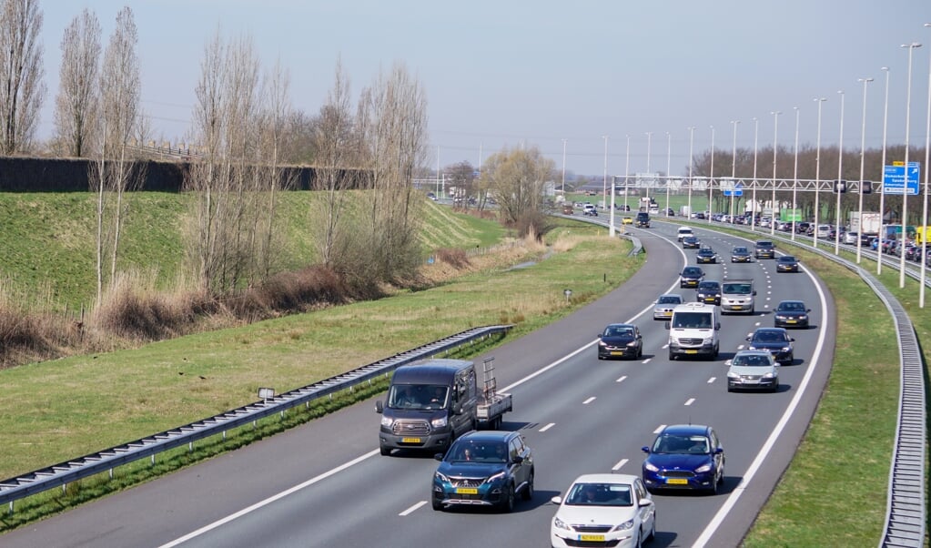 Veel verkeer op de te verbreden snelweg A1, met links de wijk Nieuwland.