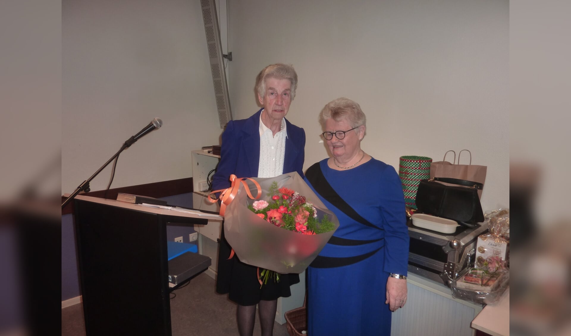Mw. H. de Kruif- Versteeg (links) 60-jaar lid Samen Verder krijgt bloemen aangeboden door Mw. H. Mons (rechts).
