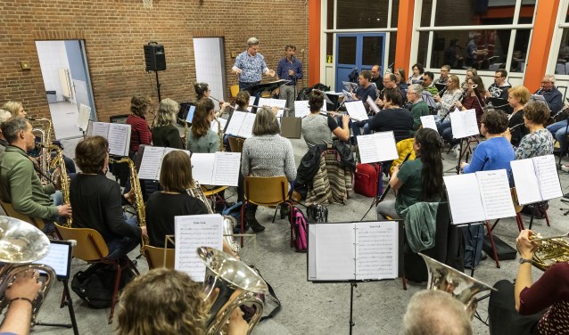 Het orkest tijdens de repetitie. Naast de dirigent (Geert Schrijvers) staat Gé Reinders.