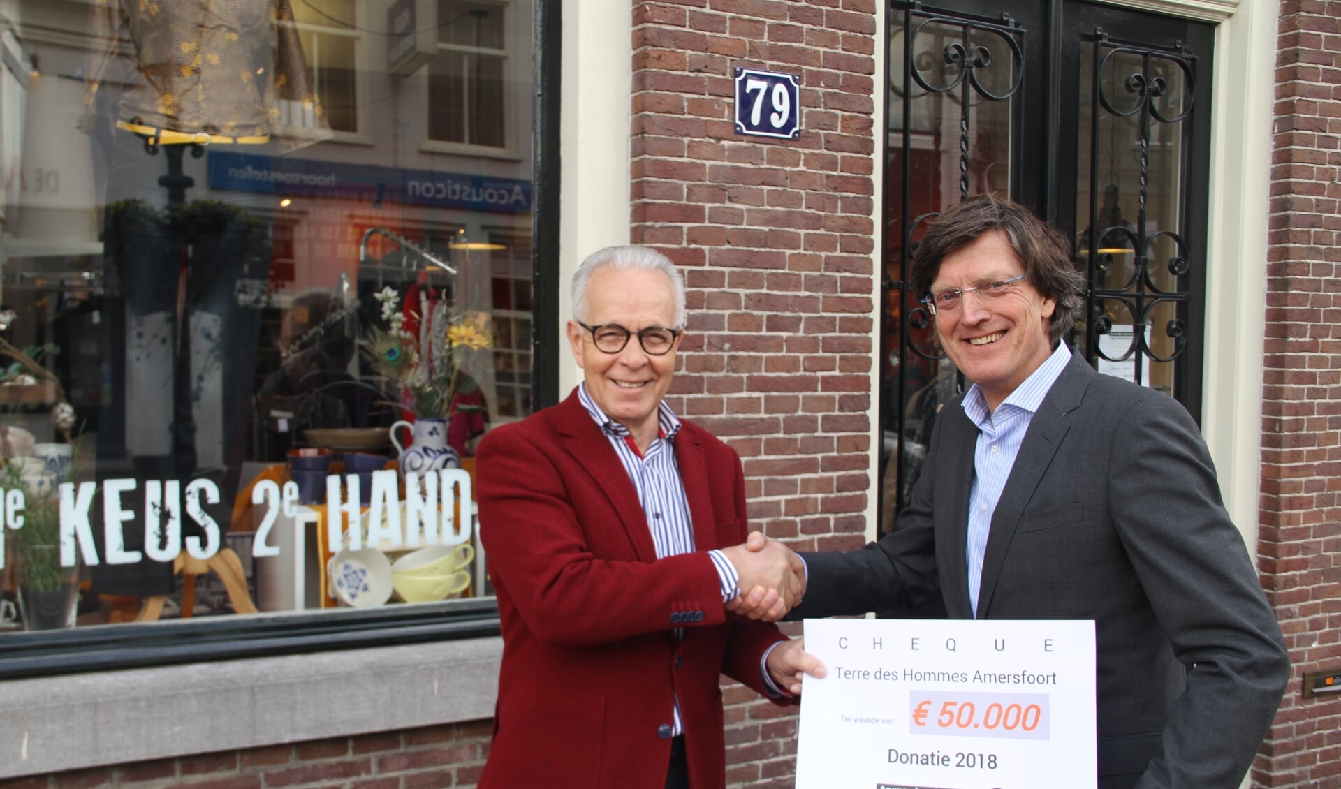 De voorzitter van Terre des Hommes Amersfoort, Hans Gelauff (links op de foto) overhandigt de cheques van € 50.000 aan Albert-Jaap Santbrink van TdH Nederland, de opbrengst 2018 van de winkel op Kamp 79 in Amersfoort