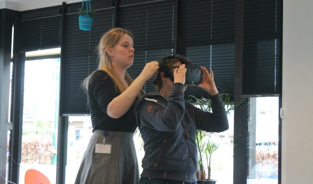 Marleen helpt Indra om de VR bril op te zetten