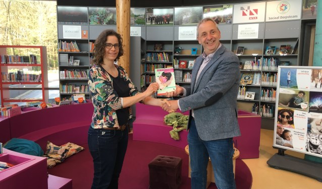 Femke Reijnen biedt wethouder Hans Waaldijk de effectmeting van de VoorleesExpress aan.