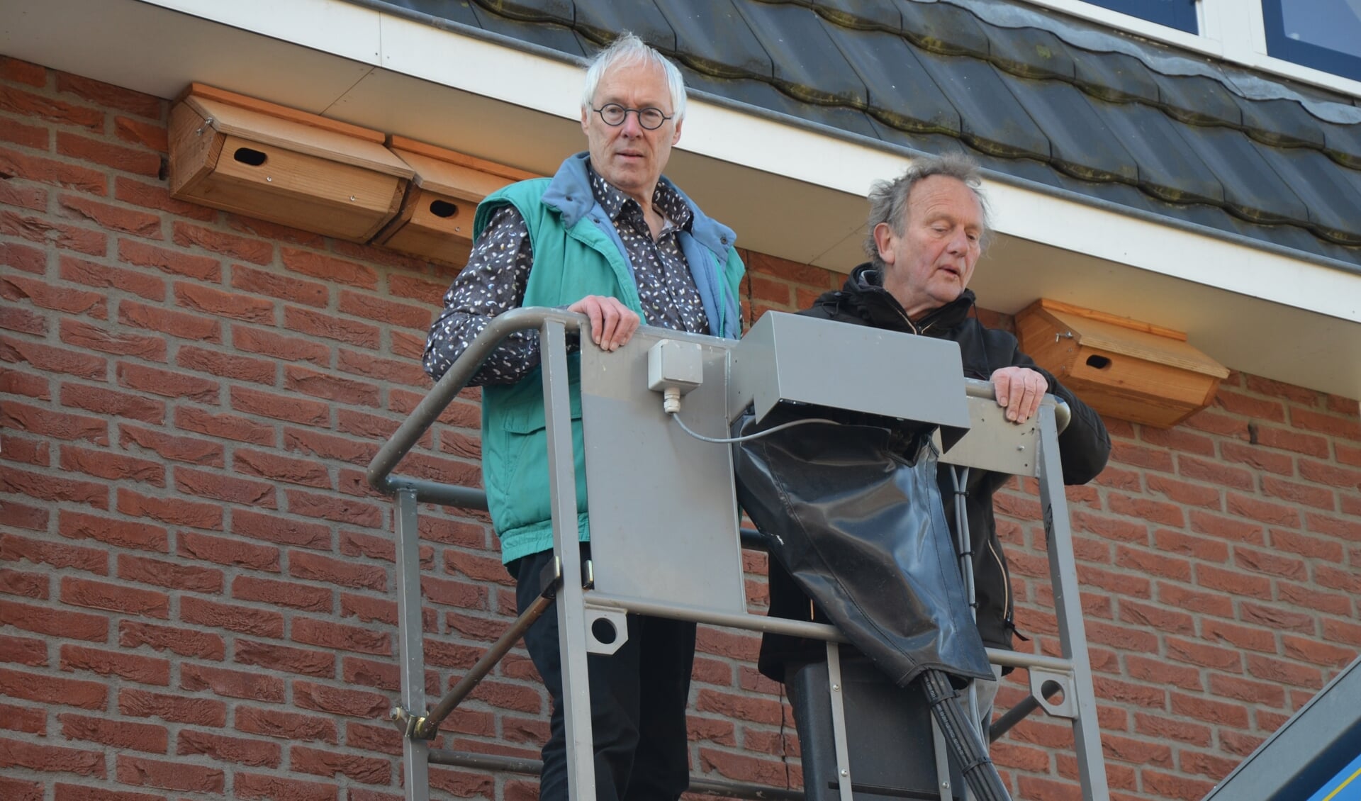 Hennie Olthof en Wim van Impelen hangen de gierzwaluwkasten op
