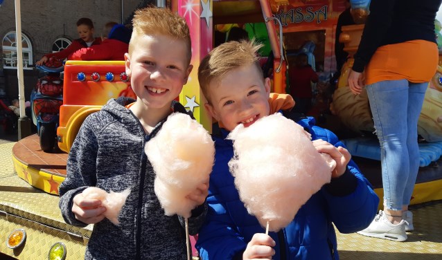 Twee jongens genieten van hun gratis oranje suikerspin.