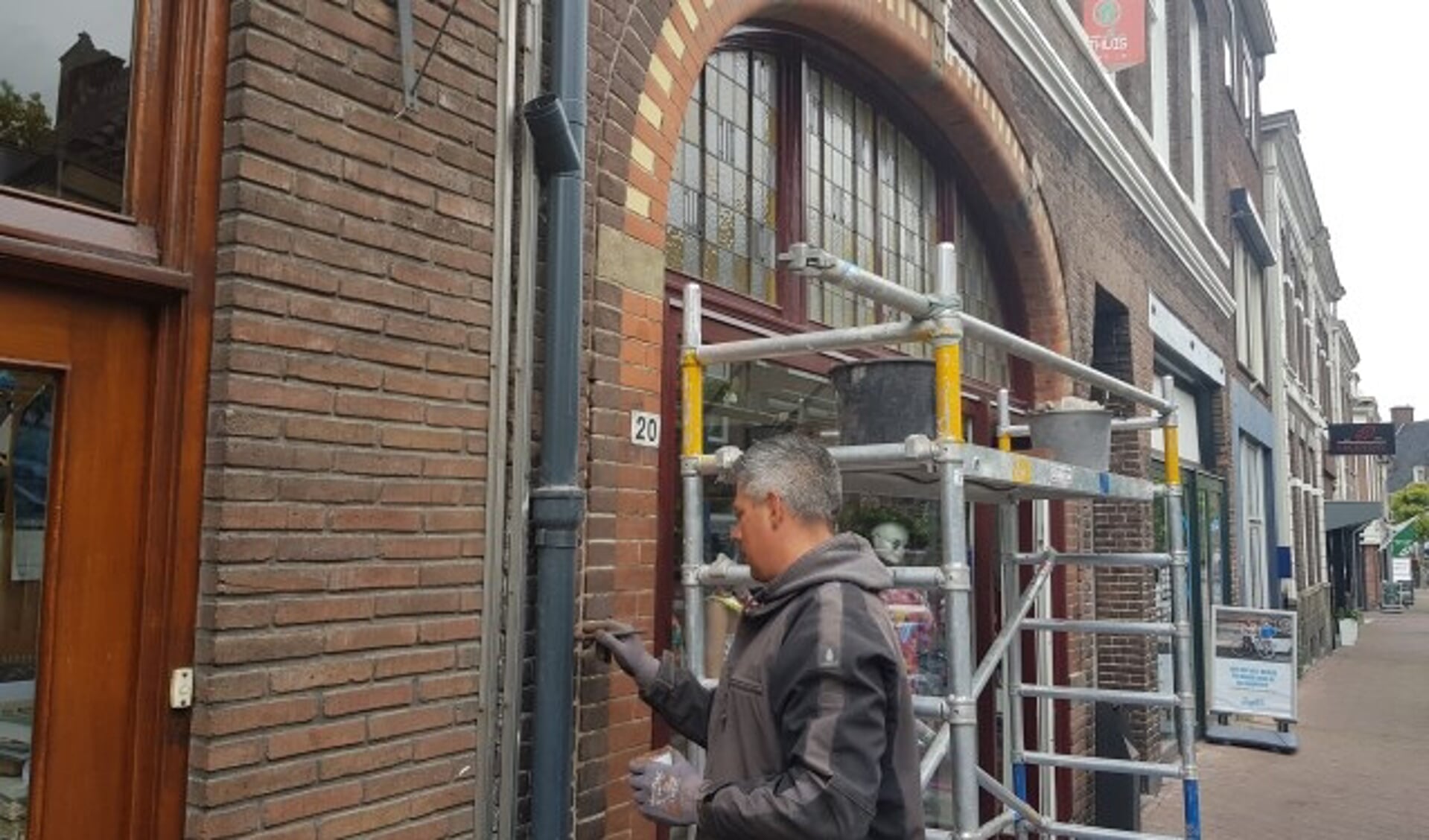 Olaf Wouters is geconcentreerd bezig om de winkelpuien aan de Bergstraat 18 en 20 van nieuwe verf te voorzien. (foto: Kees Stap)