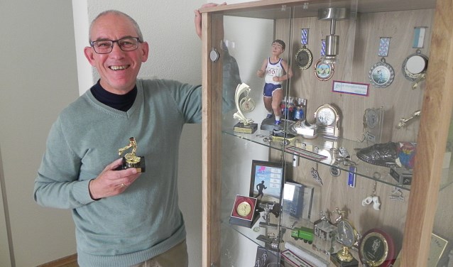Van Santen bij zijn prijzenkast met bijzondere trofeeën. In zijn hand de gouden benen die hij van vrouw Corry heeft gekregen.