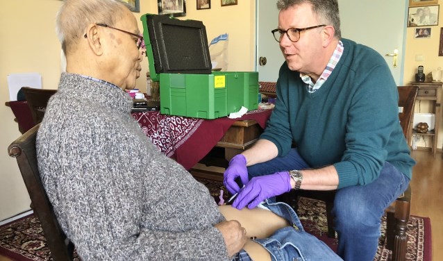 Transmuraal verpleegkundige Rob Verhoef geeft de patiënt thuis de injectie met het middel bortezomib.