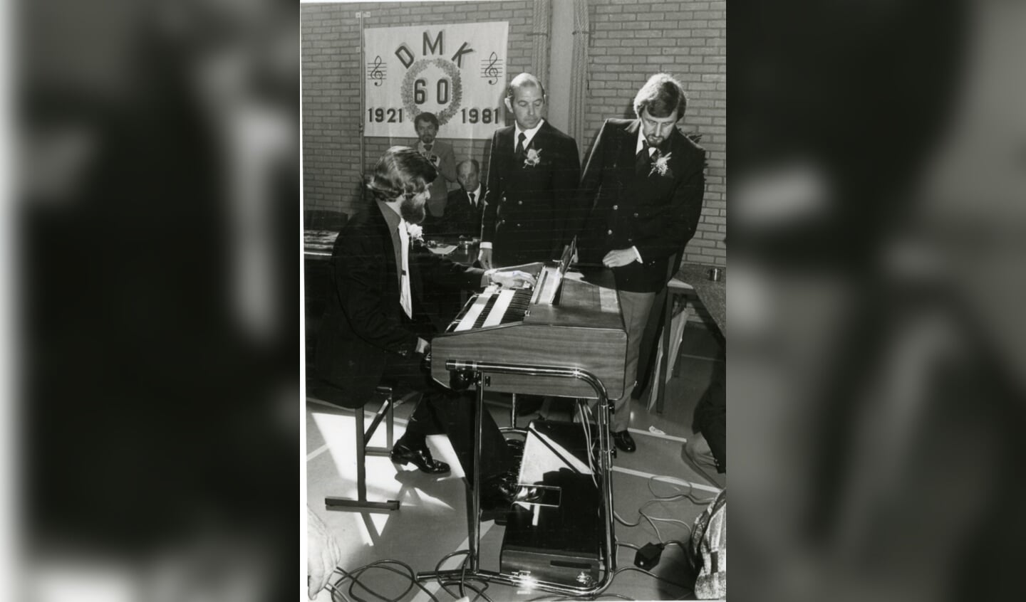 Onder bewonderende blikken van een tweetal leden wijdt dirigent Jan de Graaff het Hammond-orgel in, 1981.