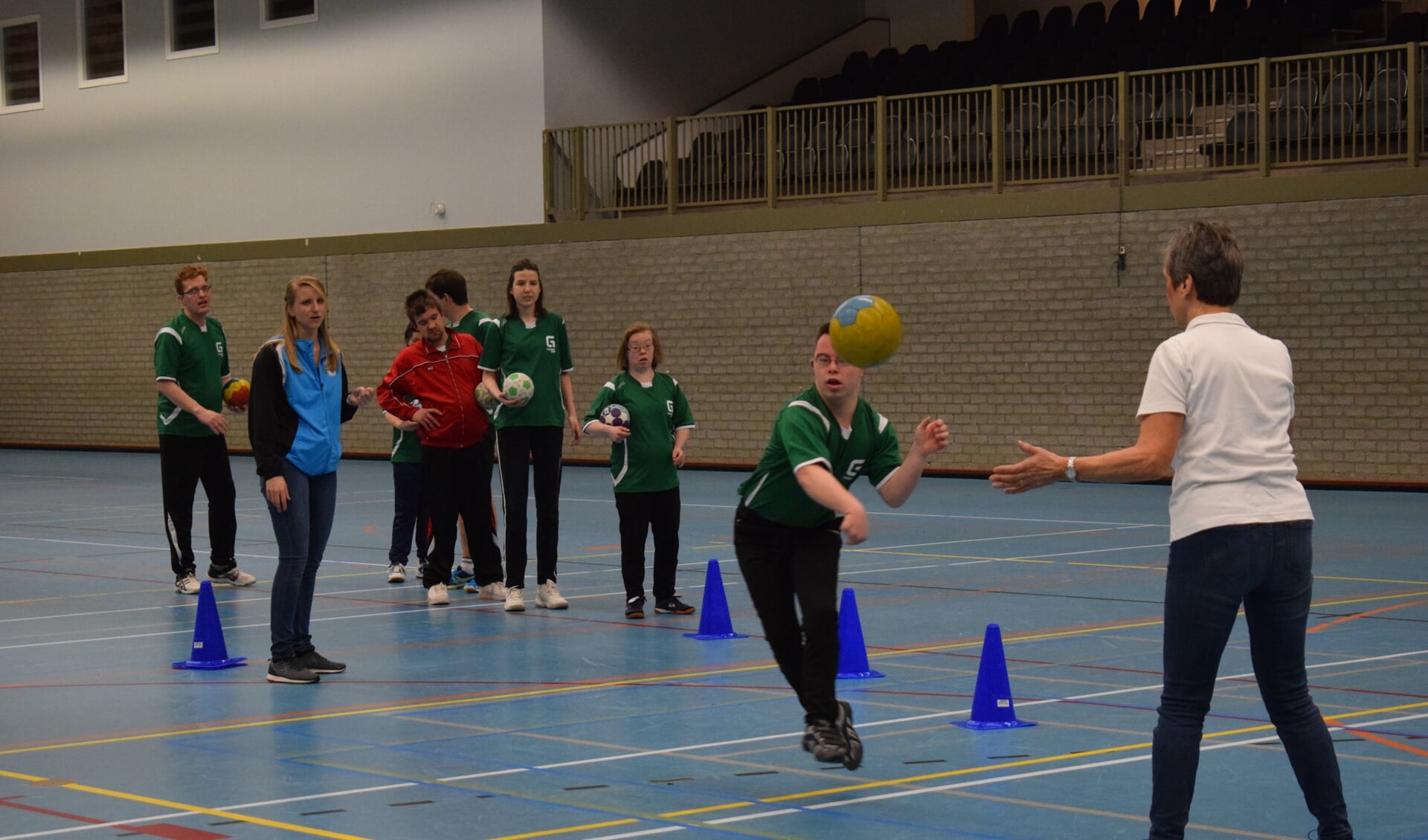 Samantha Pincetti (midden) kijkt toe als haar teamgenoot schiet. Mede door haar ouders (inzet) kan zij handballen in Baarn.