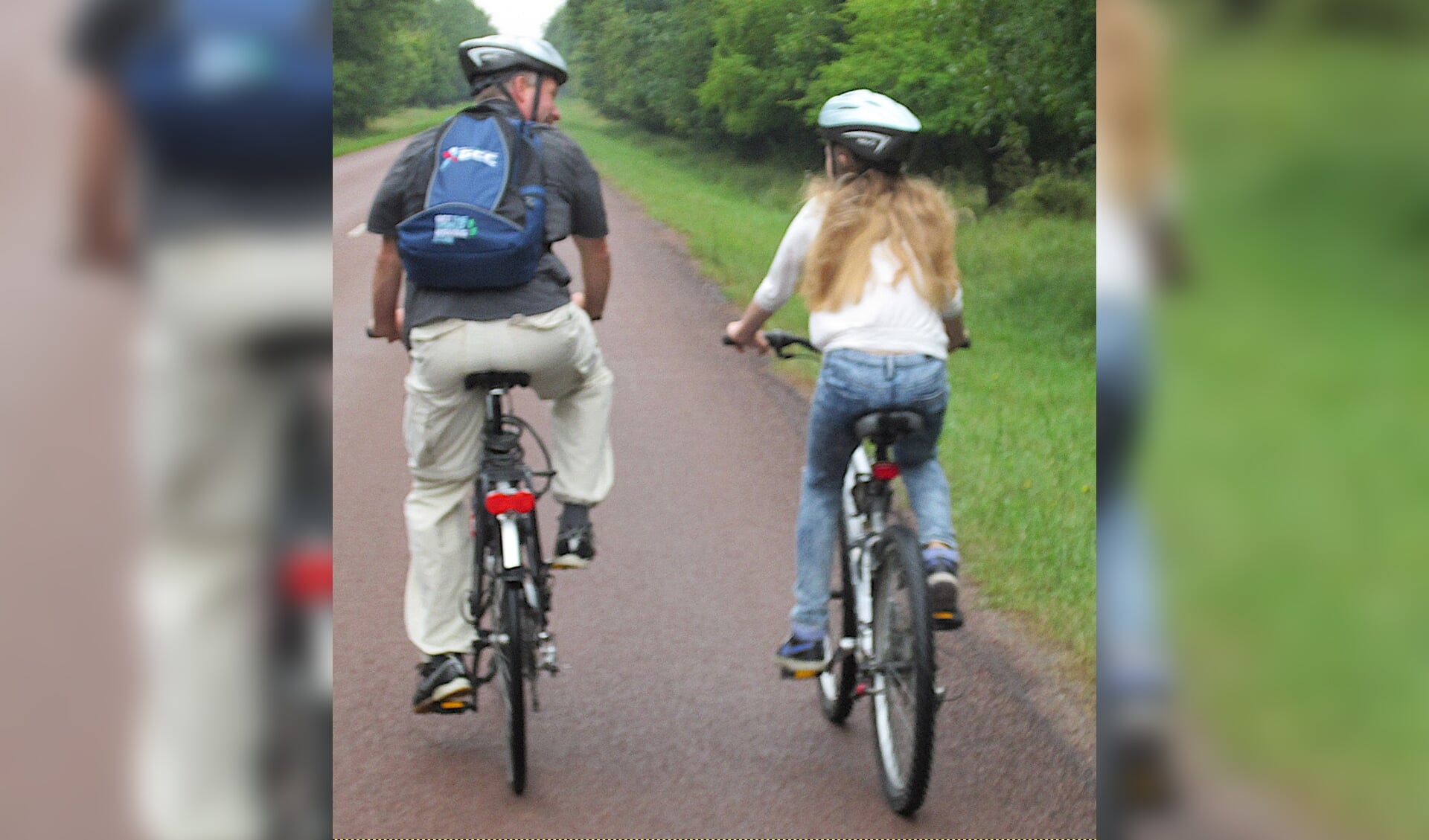 Ouder en kind fietsen samen.