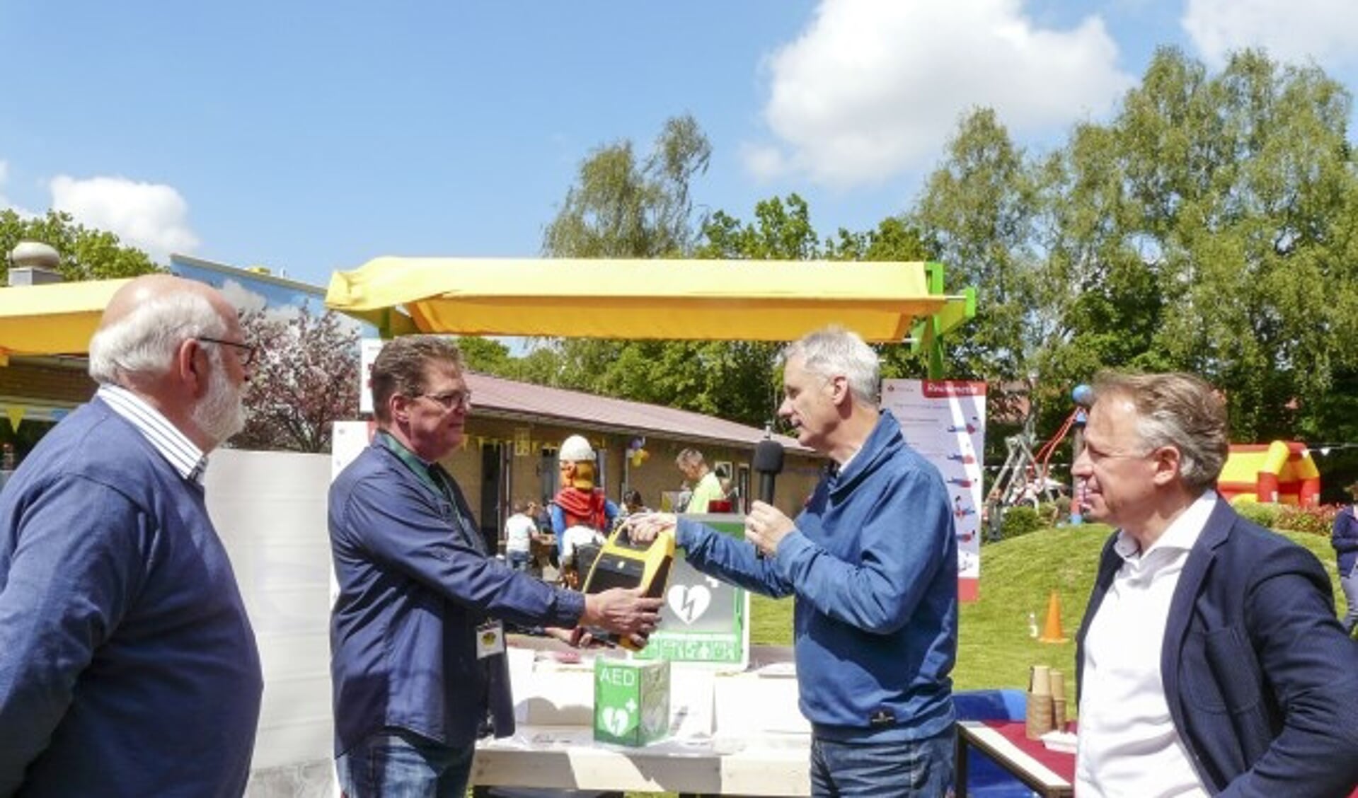 Peter Paul Tonen (Lionsclub), overhandigt de AED aan Geert Engelen (speeltuin Tuindorp). Naast hem staat Frans Seesing (Stichting Jan van Berkum) en  Bas Arents (Lionsclub). (Foto: Bob Nagel - PR-LCW)