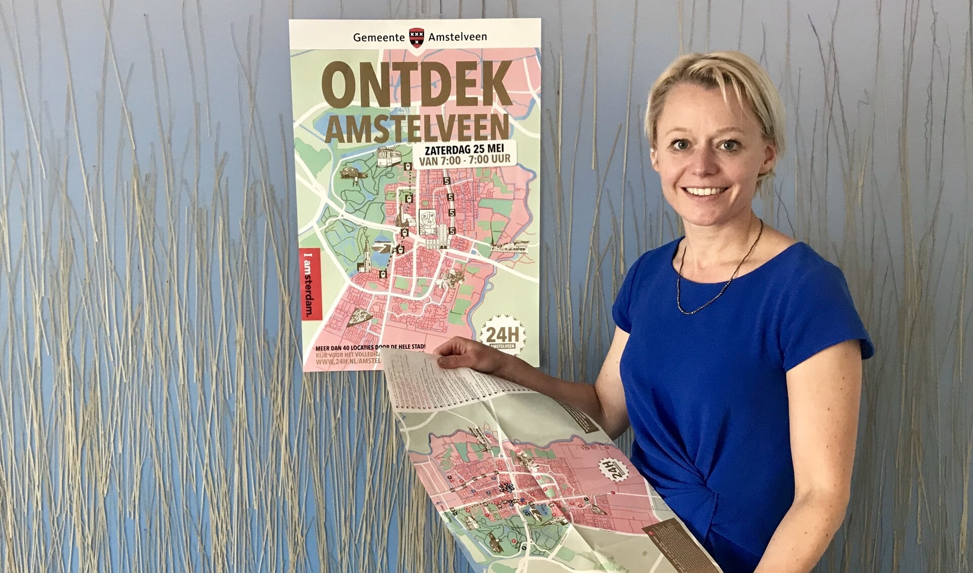 Wethouder Floor Gordon bij de poster van de eerste editie van 24H Amstelveen. Het 24 uur durende programma krijgt in september een tweede editie.