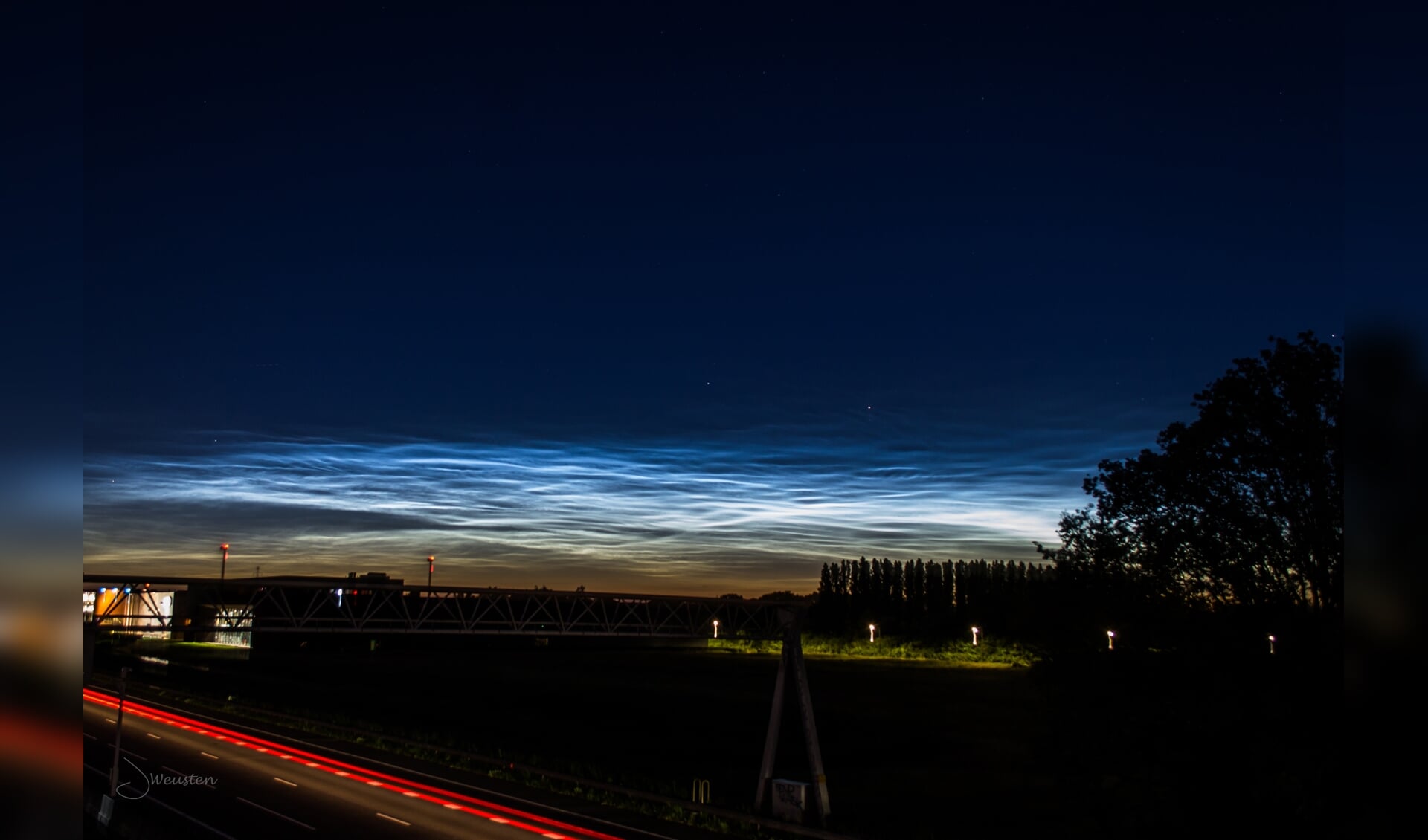 Lichtende nachtwolken boven A12 bij fietsgangersbrug Ede