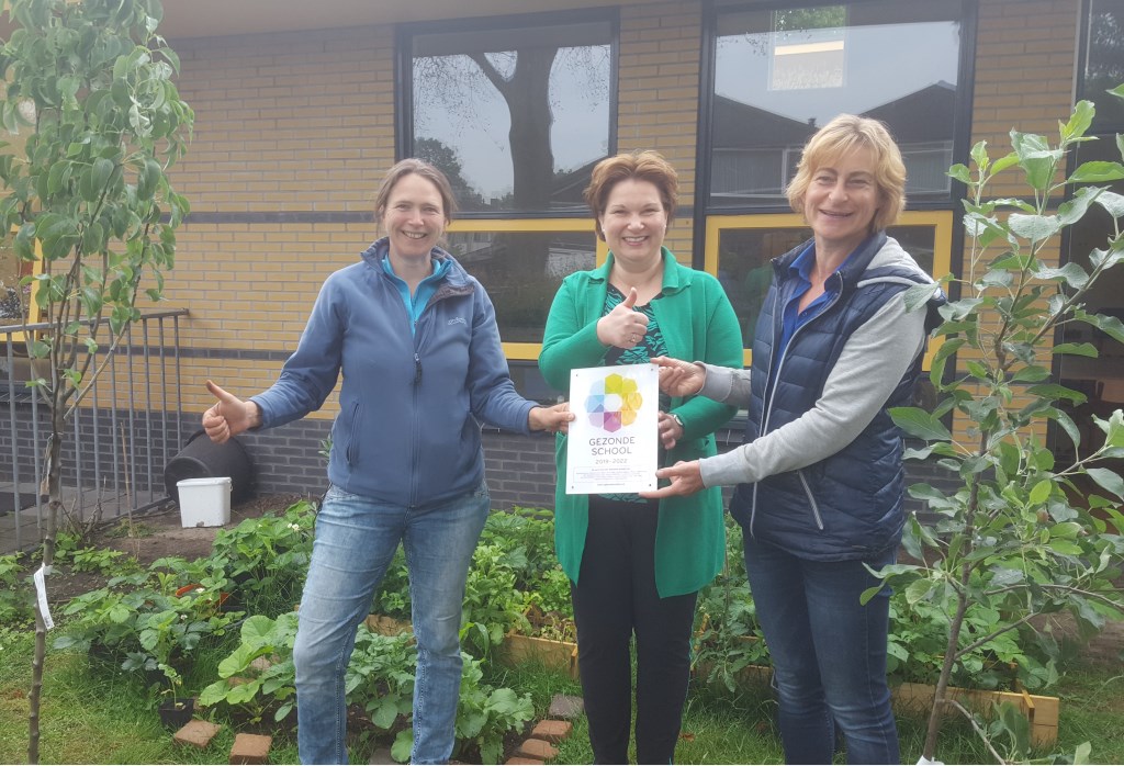Wethouder Chantal Broekhuis reikt het vignet Gezonde School uit aan natuurouders Marrit Profittlich (l) en Liesbeth van Rijsbergen (r)