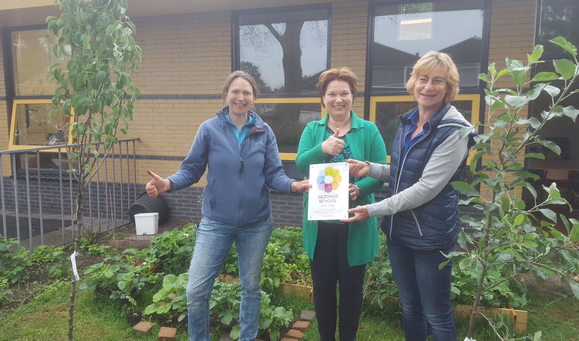 Wethouder Chantal Broekhuis reikt het vignet Gezonde School uit aan natuurouders Marrit Profittlich (l) en Liesbeth van Rijsbergen (r)