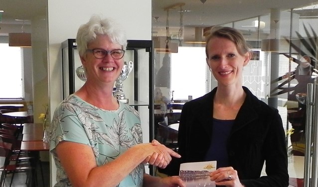 Wethouder Jana Smith-Visser ontvangt het programmaboekje uit handen van voorzitter Annemieke Hoogenhout.