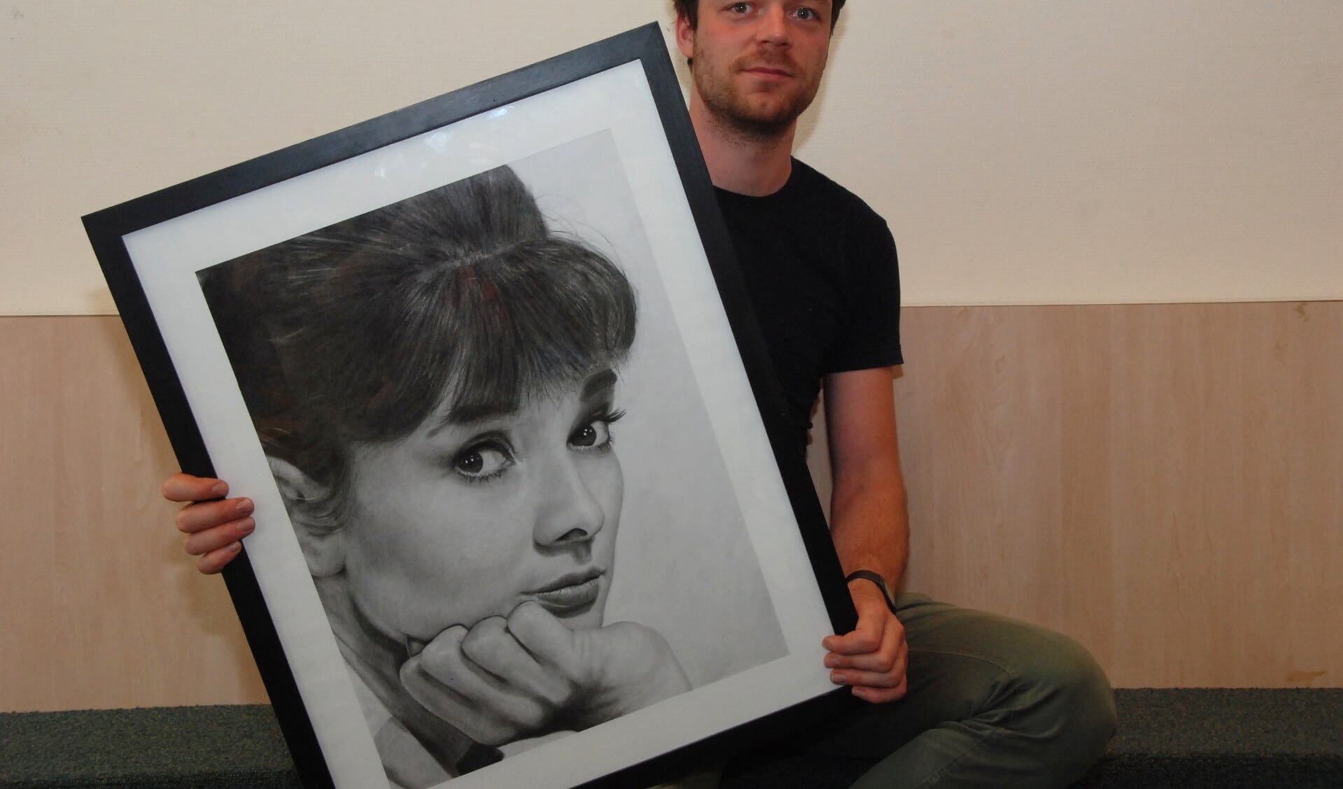 Martijn Versteeg met een portret van Audrey Hepburn.