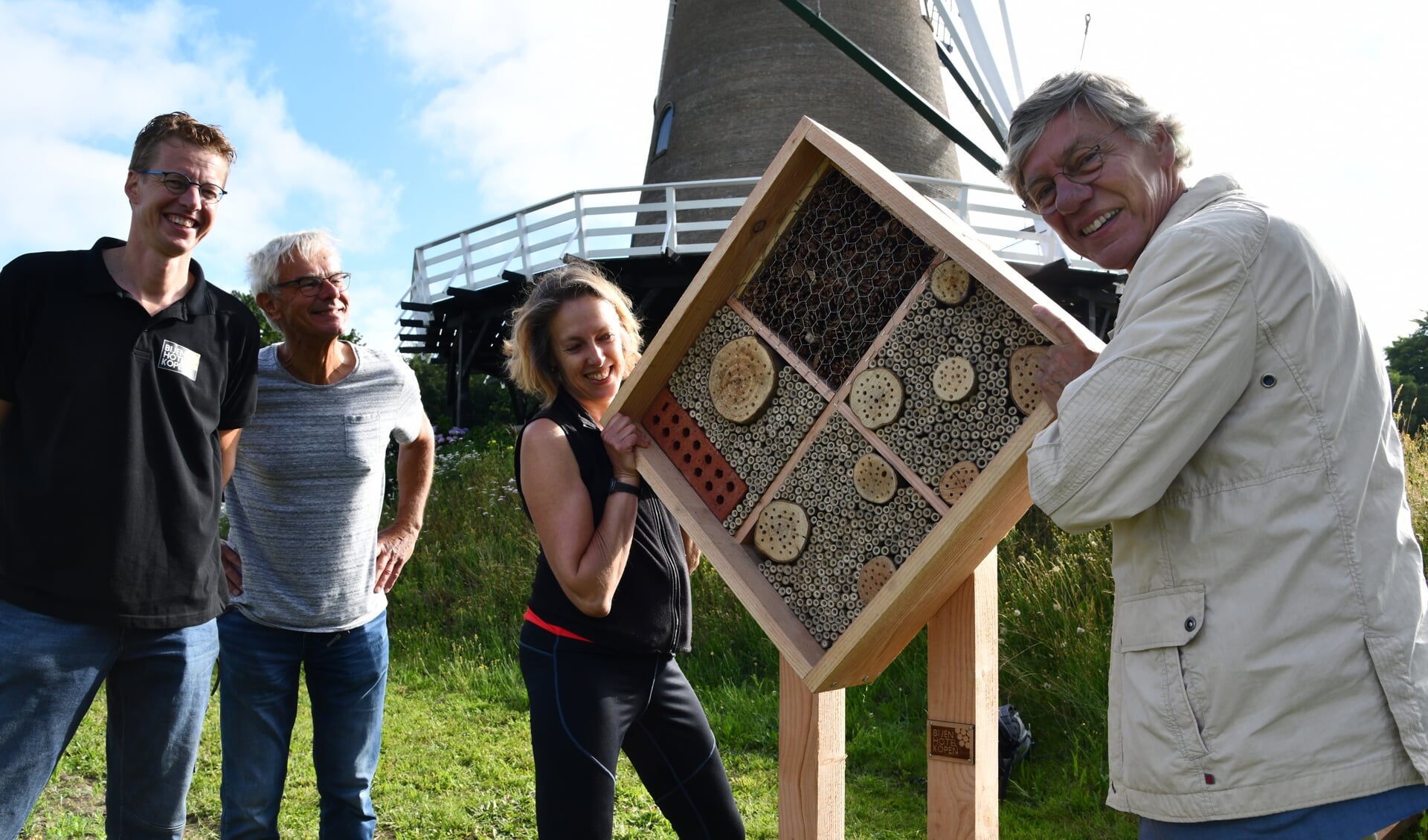 Leon Gerrits en molenaar Wim Endendijk kijken toe hoe Alexandra Tom en Kees Waagmeester zich ontfermen over het bijenhotel.