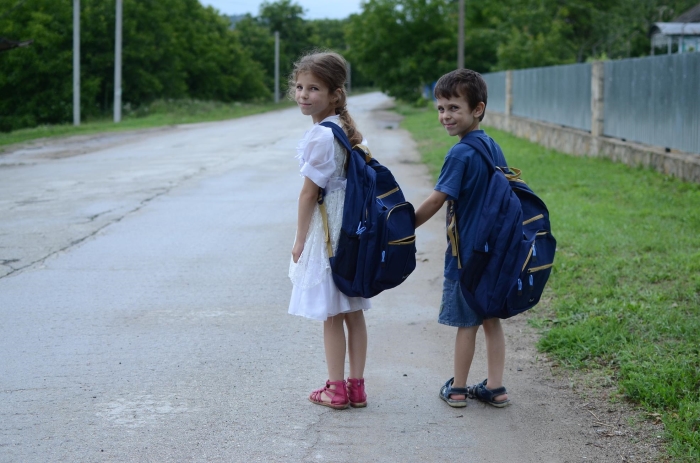 Oost-Europese kinderen op weg naar school met goed gevulde rugzak schoolspullen