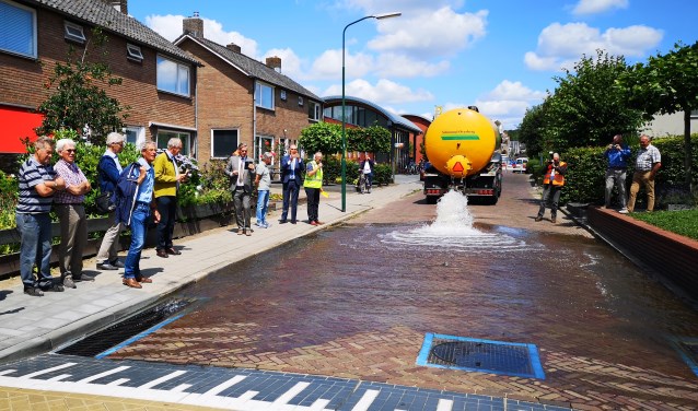 Belangstellenden, waaronder burgemeester Naafs (midden), zagen dat het nieuwe afwateringssysteem prima werkt.