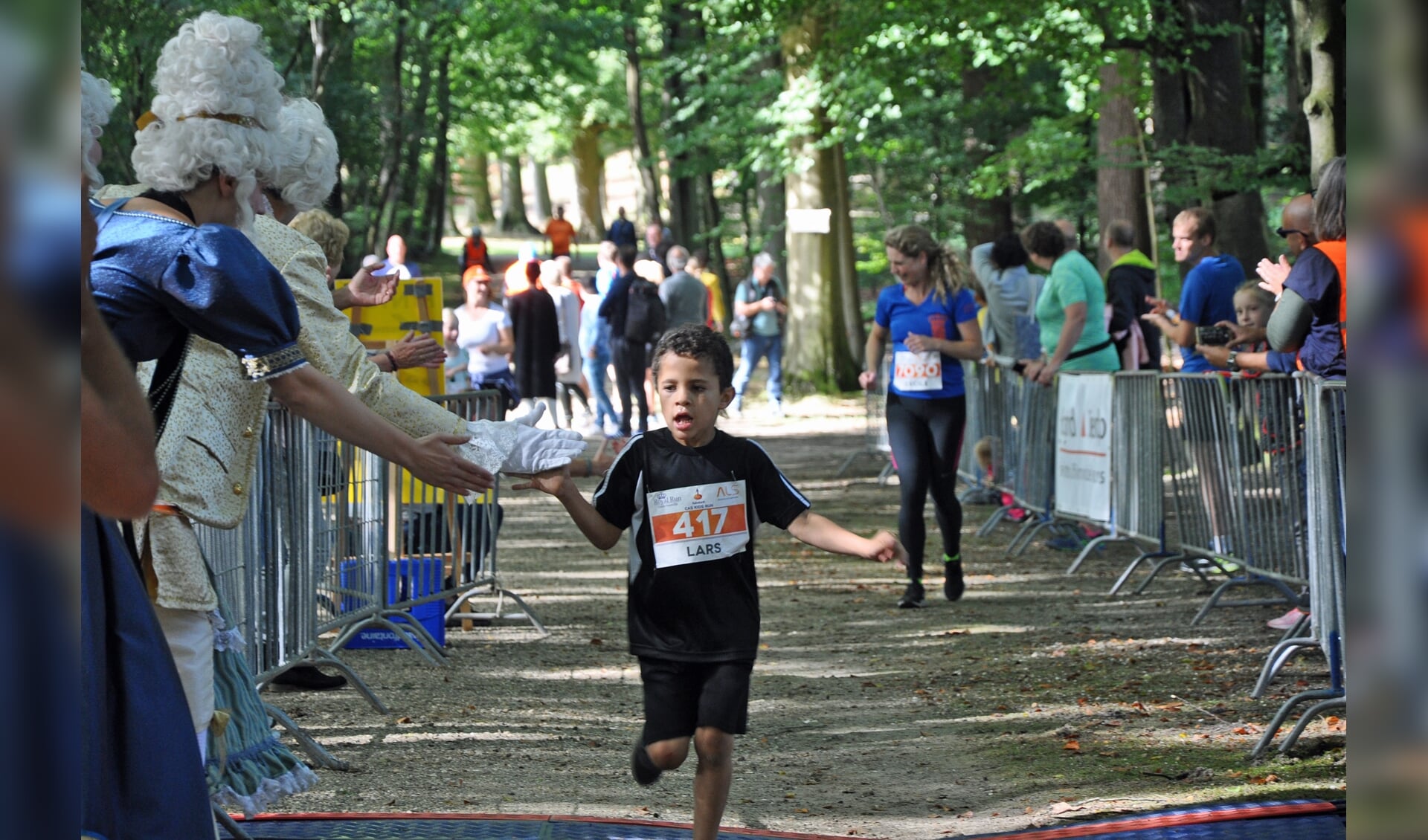 Een trotse Lars wordt bij de finish onthaald door een hofdame en een lakei.