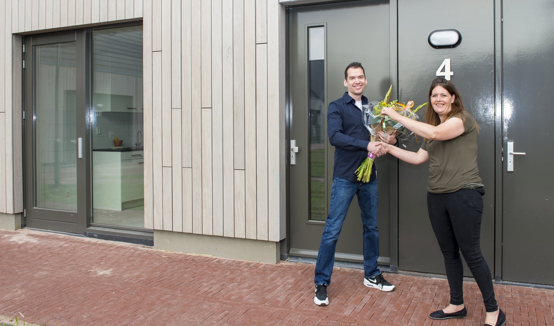 Alliantie-medewerker Albertina Middelbos-van Wijk overhandigt de sleutel aan de eerste bewoner Barry van de sociale huurwoningen in Vathorst (Amersfoort).