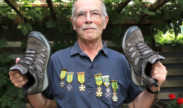 Marcel Vermaas in de tuin met zijn medailles en wandelschoenen. ,,Elk jaar ben ik uitgeput na de Vierdaagse en zeg ik dat ik niet meer mee doe. Maar in het volgend voorjaar krijg ik de kriebels en ga ik toch weer trainen."