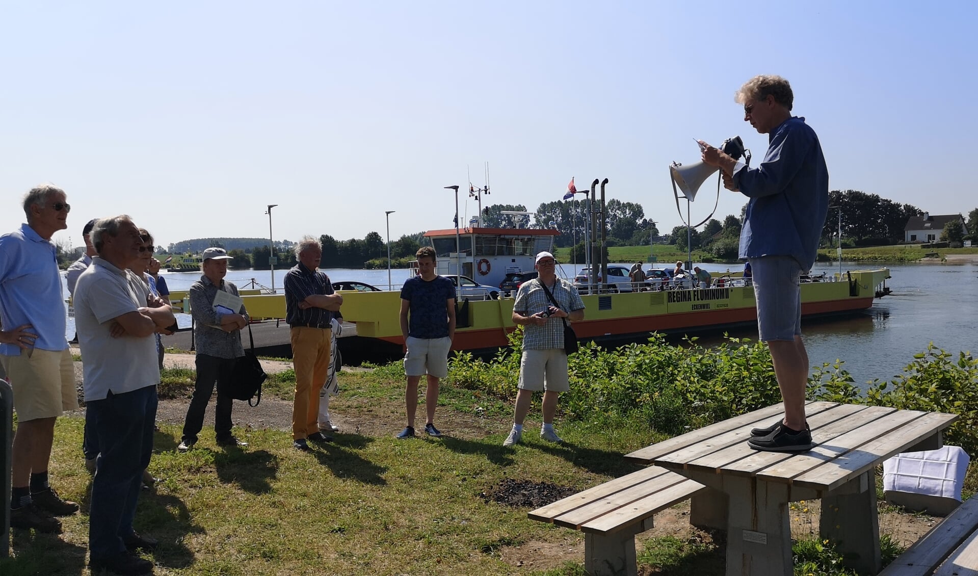 Stadsdichter van Wijk bij Duurstede André van Zwieten leest het eerste couplet voor bij de picknickbank op de veerstoep.