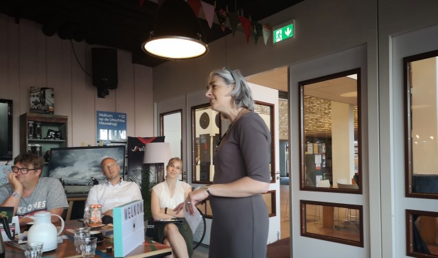 Gera Pronk draagt haar gedicht 'Een dorp van zes miljoen' voor, Maja van Eijndthoven luistert aandachtig mee.