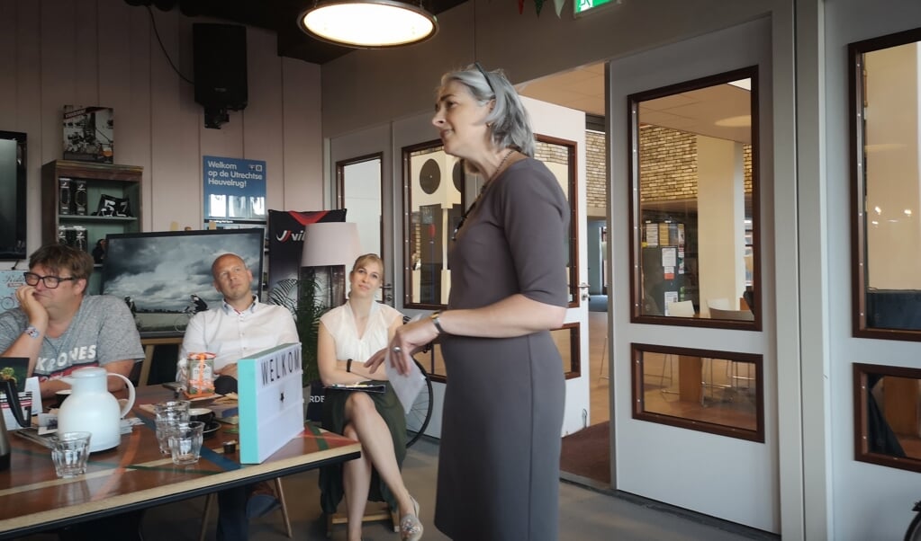 Gera Pronk draagt haar gedicht 'Een dorp van zes miljoen' voor, Maja van Eijndthoven luistert aandachtig mee.
