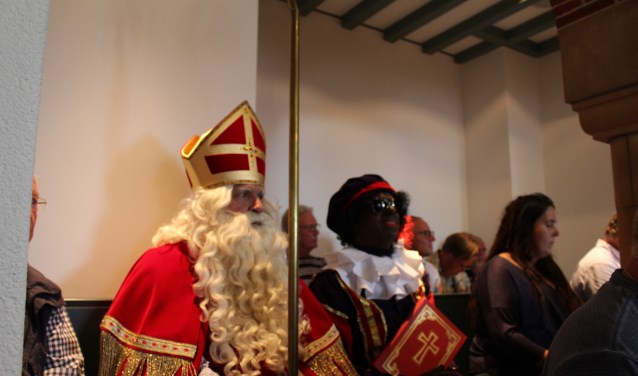 Sinterkaas en zijn hoofdpiet op de publieke tribune in de raadszaal tijdens het debat over subsidie voor het Sinterklaasfeest.