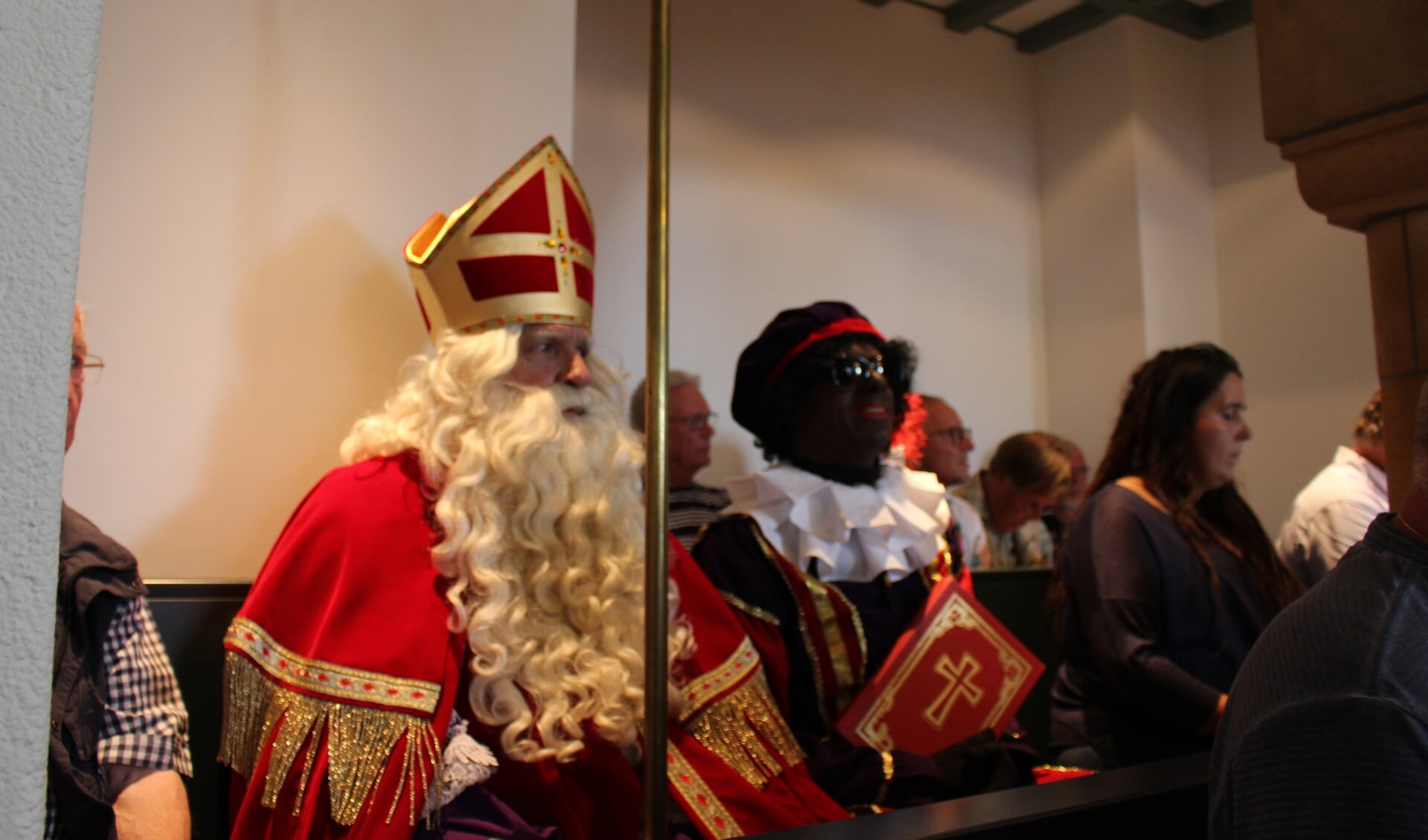 Sinterkaas en zijn hoofdpiet op de publieke tribune in de raadszaal tijdens het debat over subsidie voor het Sinterklaasfeest.