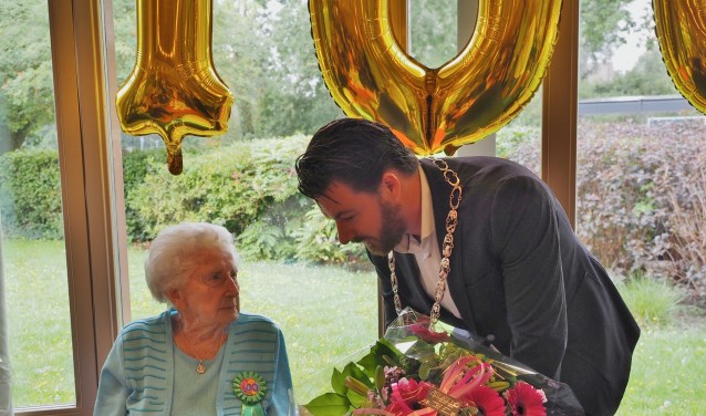 Robbert Berkhout overhandigt een grote bos bloemen van de gemeente aan Miep van Esdonk vanwege haar verjaardag.