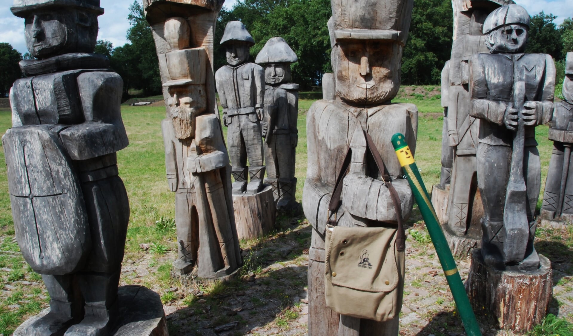 Een houten soldaat met in z'n hand de tas met opdrachten en het paaltjes, zoals die langs de route voor de jeugd te vinden is.
