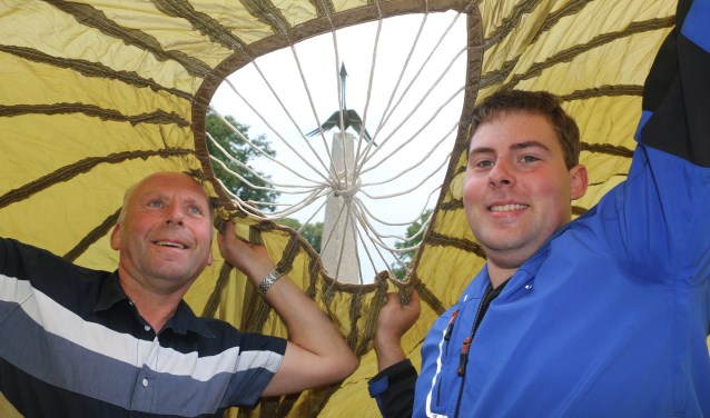 Vader Kees en zoon Remco onder het doek met zicht op het monument met de vogel.