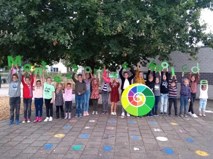 Leerlingen van de Montessorischool houden het nieuwe Logo vast
