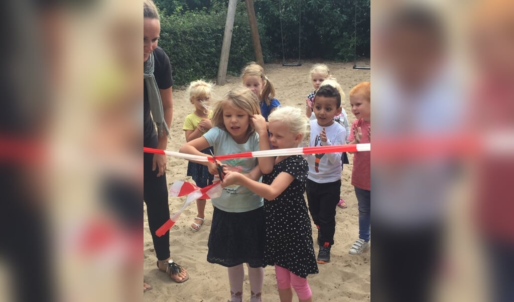 Twee leerlingen van De Zevensprong openen het speeltoestel op de eerste schooldag