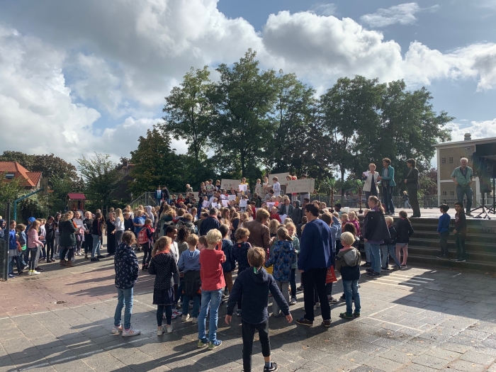 Leerlingen bieden tekeningen aan aan wethouder