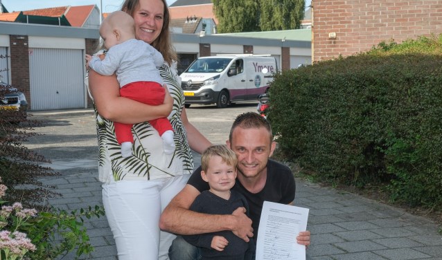 Het gezin Van Diel, met Robert die de handtekeningenactie toont. Op de achtergrond een van de busjes van Ymere die volgens hem de buurt gevaarlijk maken.