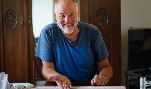 Naast het vrijwilligerswerk mag Hans graag wandelen. Hij loopt al jaren mee met de Nijmeegse Vierdaagse. Hij toont zijn mooiste Vierdaagsekruisje.