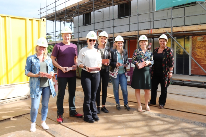 Toekomstige bewoners leggen samen met directeur-bestuurder Marije Buursink de eerste steen van hun nieuwe woning.