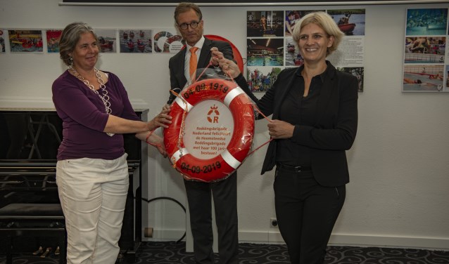 Koen Breedveld, directeur Reddingsbrigade Nederland, overhandigt een cadeau aan Jannechien Peek en burgemeester Nienhuis.