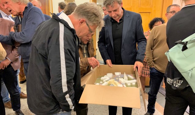 Het publiek buigt zich over de maquette na afloop van de infoavond in het gemeentehuis.