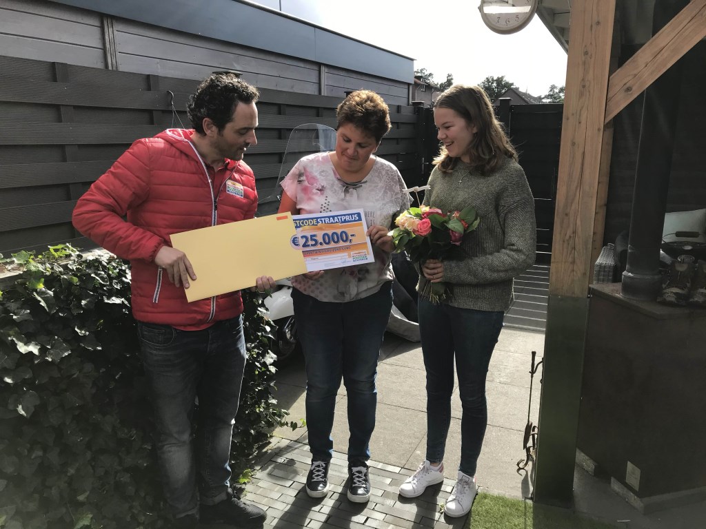 Echtgenote en dochter van winnaar Jan uit Wekerom worden verrast door de Postcode Loterij met de PostcodeStraatprijs-cheque.