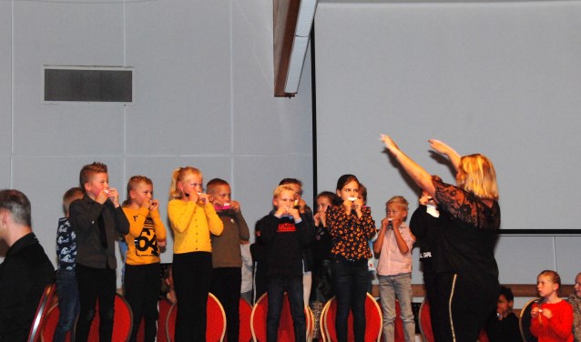 Scholieren spelen, staande op de stoelen, muziek op een kammetje.