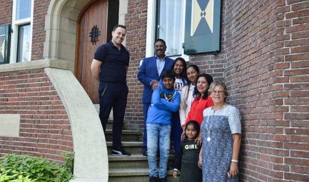 Burgemeester Cnossen voor het gemeentehuis met zeven nieuwe Nederlanders.