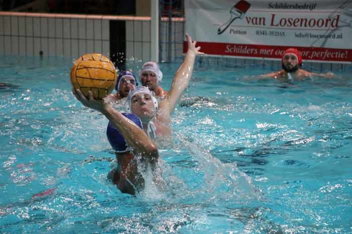 Jens Slofstra (witte cap) probeert zijn tegenstander van scoren af te houden. Slofstra had met 2 doelpunten een belangrijk aandeel in de overwinning.