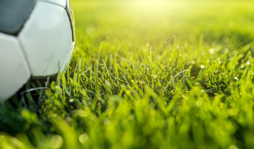 Photo of Traditional soccer ball on green  soccer field during bright sunny day.